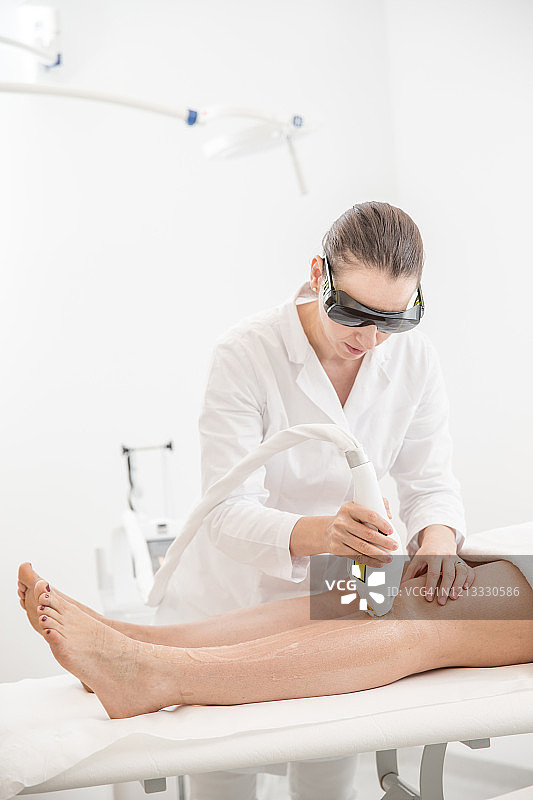 皮肤科医生用二极管激光从病人的腿上去除毛发图片素材