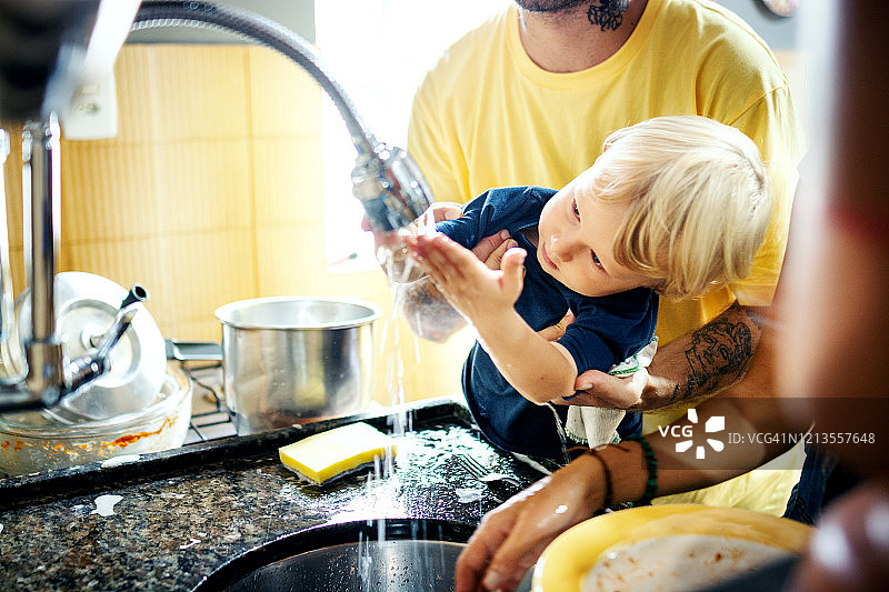 可爱的小男孩和他的爸爸在厨房洗盘子图片素材