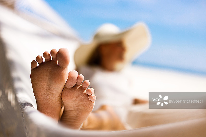 躺在沙滩吊床上的女人的脚。图片素材