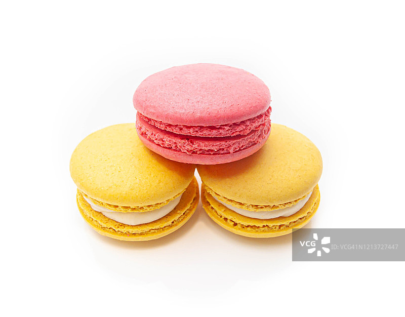 三个金字塔形的杏仁饼干，一个粉色，两个黄色，在一个孤立的白色背景上图片素材