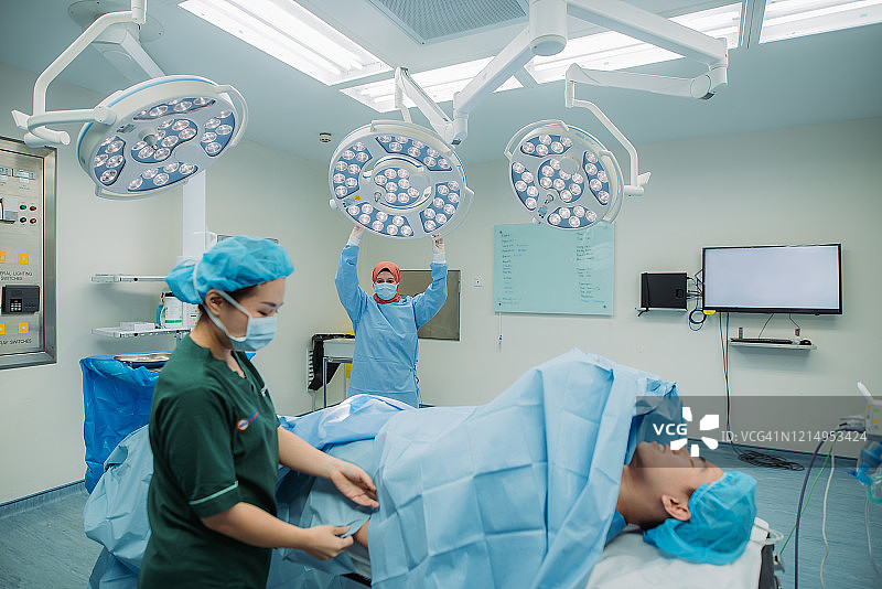 亚裔华裔女护士在医院手术室术前调整手术灯的位置图片素材