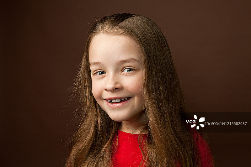 一个9岁小女孩的画室肖像，背景是棕色图片素材