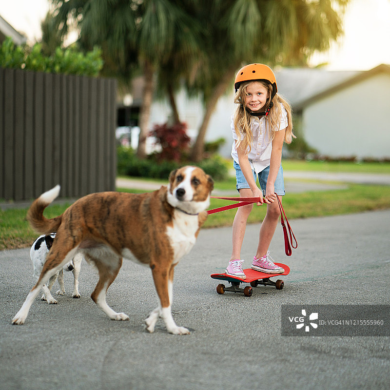 小女孩和她的狗玩滑板图片素材