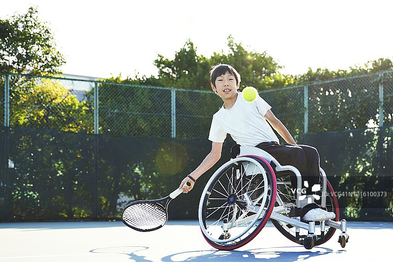 年轻男子坐在轮椅上在网球场上打网球图片素材