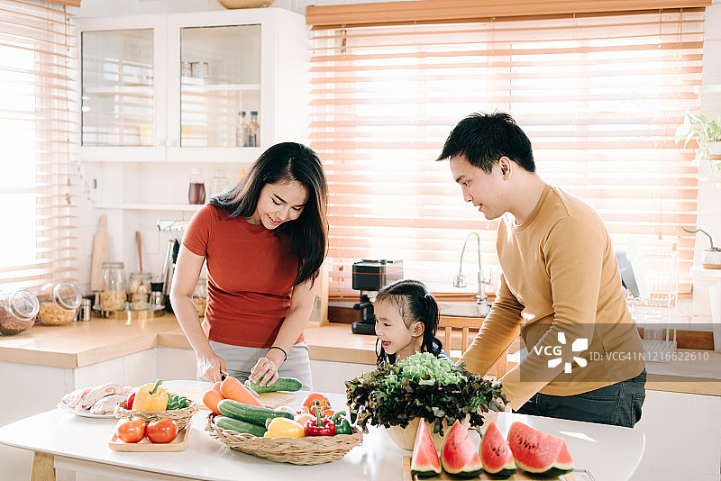 亚洲家庭为了健康在厨房里一起做饭图片素材