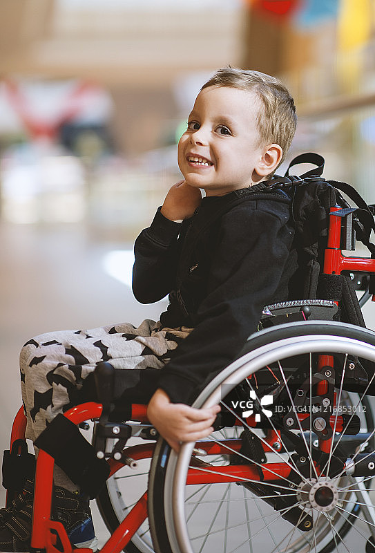 在商场里坐轮椅的可爱小男孩图片素材