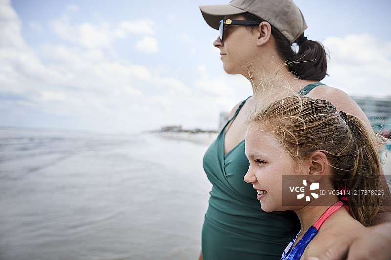 母亲和女儿在海滩上向外看图片素材