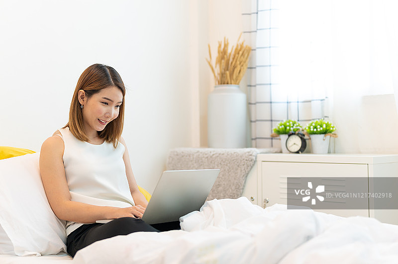 年轻的亚洲女性使用笔记本电脑在家工作图片素材