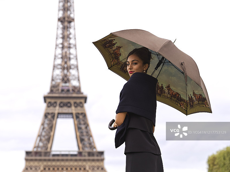 法国巴黎埃菲尔铁塔前撑伞的时髦女人的肖像图片素材
