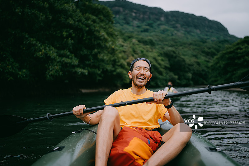 一名男子笑着在红树河中划着皮艇，Iriomote，日本图片素材