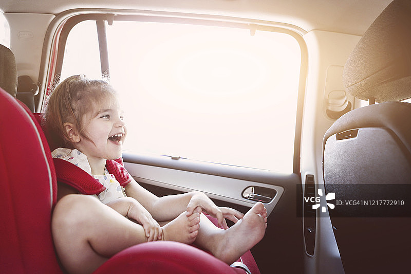可爱的小女孩在汽车安全座椅微笑图片素材