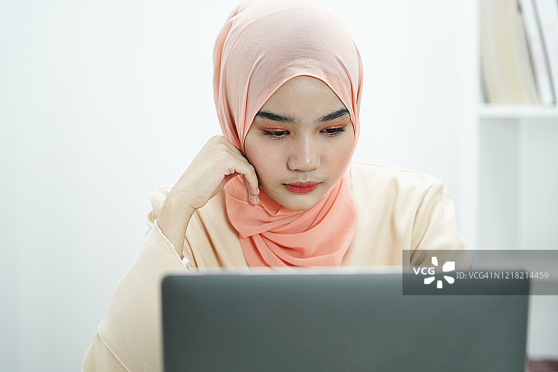 紧张的穆斯林女商人感到疲倦，而在办公室的笔记本电脑前工作图片素材
