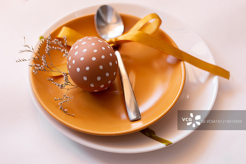 复活节时，在黄白相间的盘子上涂上各种白色图案的棕色彩蛋，并配上香草。带黄色丝带的勺子。传统的东欧文化。俯视图图片素材