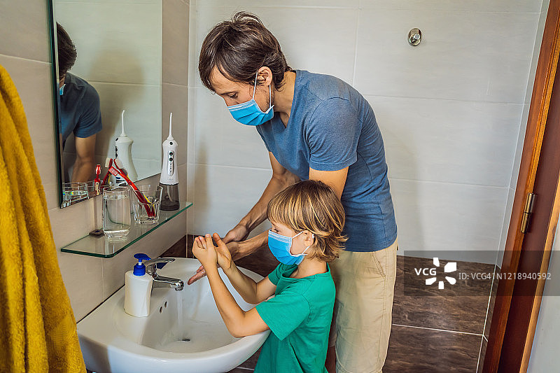 爸爸教儿子正确洗手。因为冠状病毒，爸爸和儿子戴着医用口罩。疫情呆在家里。洗你的手图片素材