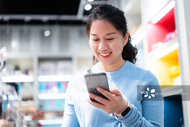 女性在超市用智能手机购物图片素材