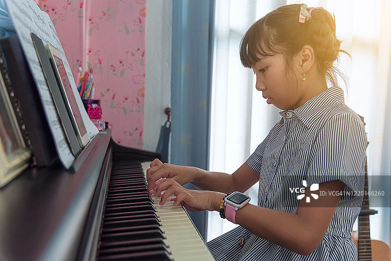 女孩在家里弹钢琴。图片素材