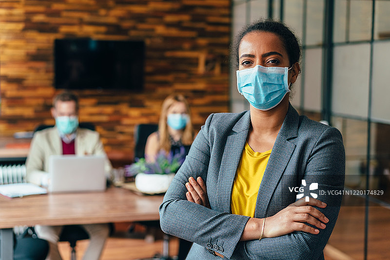 2019冠状病毒病大流行期间在办公室工作佩戴口罩的商务人士图片素材