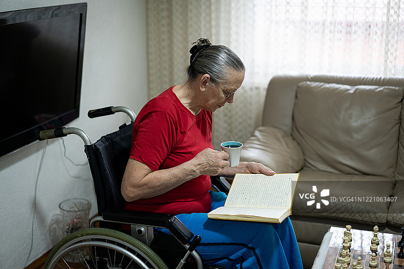 老年妇女在轮椅上看书图片素材