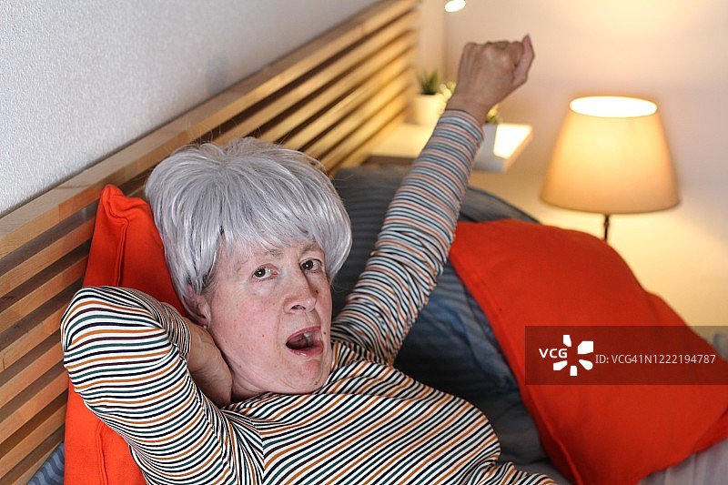 懒惰的老女人在床上打哈欠图片素材