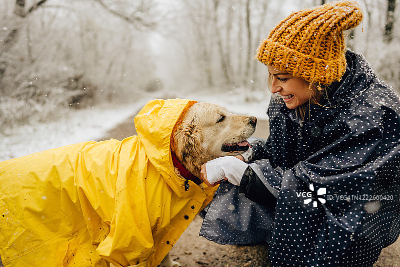 微笑的女人和她的狗在冬天散步图片素材