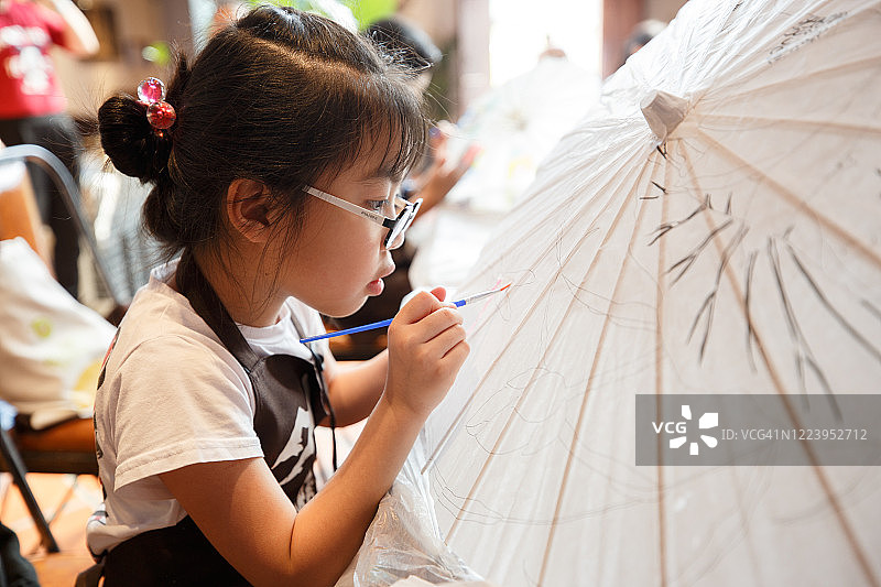 中国小孩喜欢做手工，在中国传统的纸伞上画画图片素材