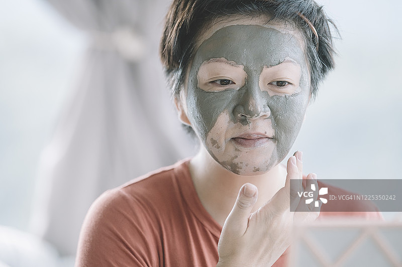 一位亚洲华人中年女性正在准备化妆，在家里脸部水疗，纵容自己的粘土面膜皮肤护理图片素材