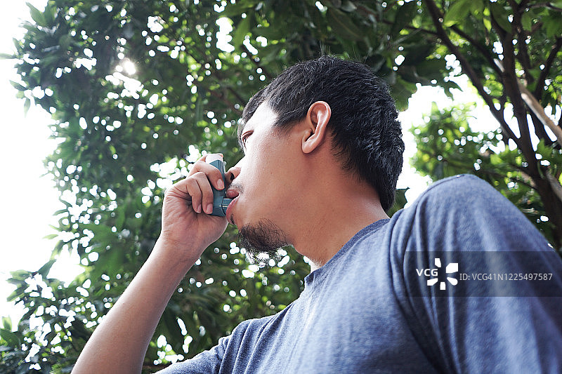 亚洲年轻人使用哮喘吸入器图片素材