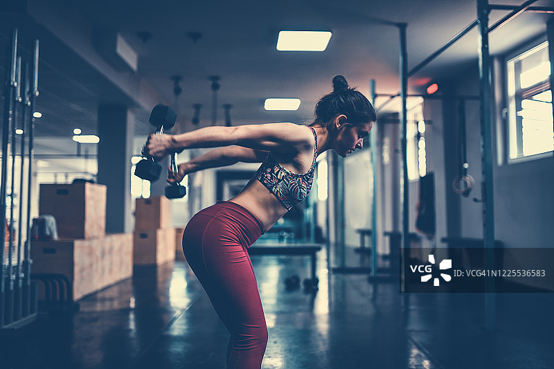 女性在健身房用哑铃锻炼肱三头肌图片素材