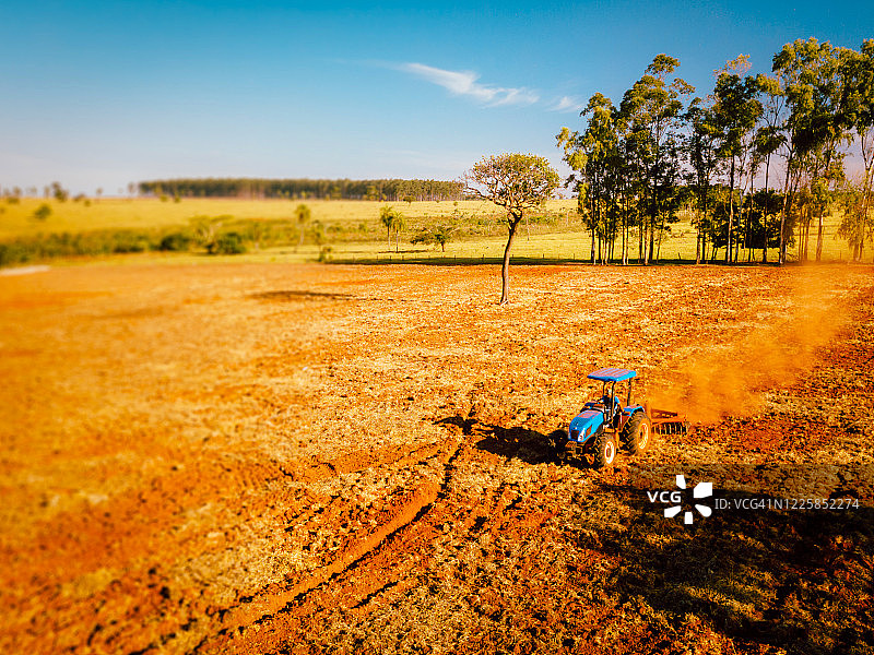 鸟瞰图的农民准备土壤种植与犁拖拉机-准备土地在农场。农业的概念图片素材
