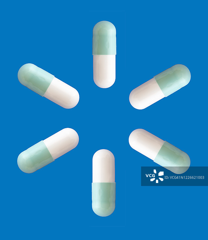 药丸和胶囊在蓝色的背景上形成一个圆圈。图片素材