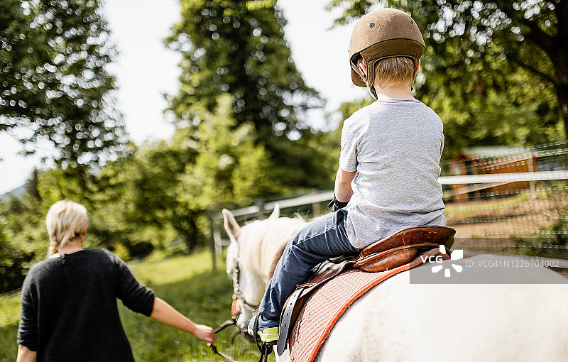 一个年轻女子教一个男孩如何骑马图片素材