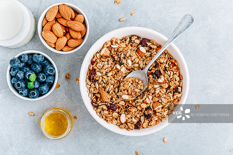 格兰诺拉麦片搭配新鲜的蓝莓、杏仁、牛奶和蜂蜜作为早餐。图片素材
