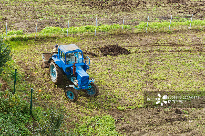 蓝色拖拉机给田地施肥，农民用铁锹撒肥料，给田地施肥图片素材