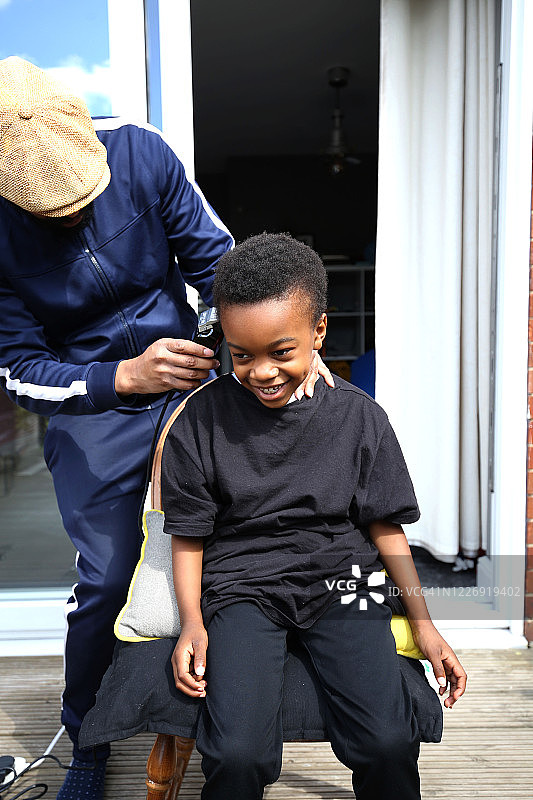 黑人男孩在花园里修剪头发图片素材