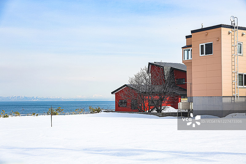 日本北海道小taru的色彩斑斓的房子，沿着冰雪覆盖的太平洋，后面是山脉图片素材