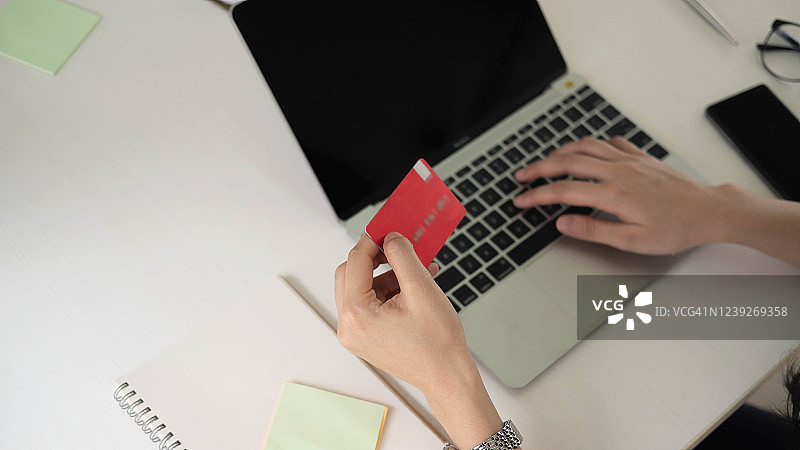 一个女人用笔记本电脑用信用卡在网上购物图片素材