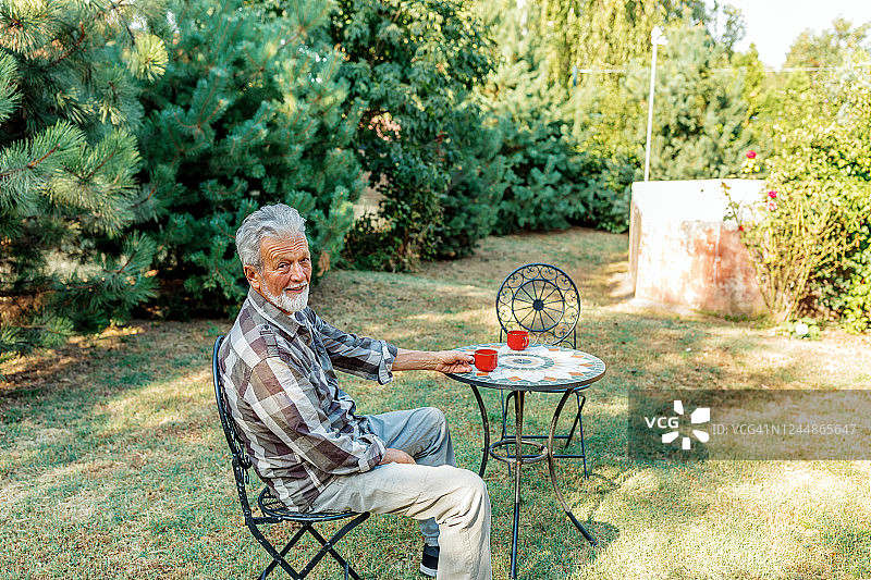 大胡子老人在自家后院喝咖啡图片素材