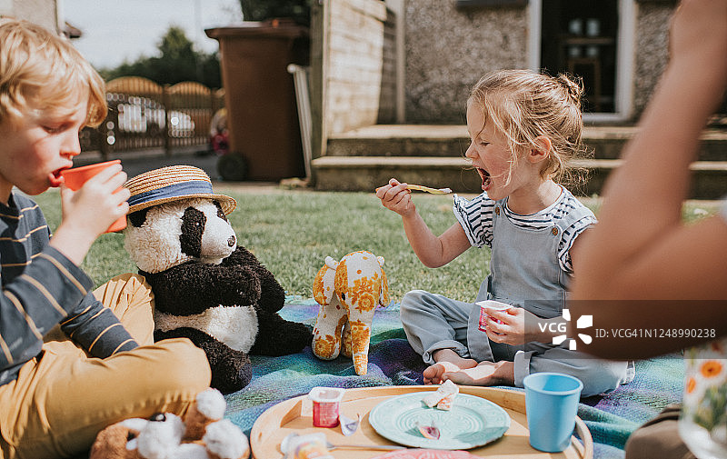 孩子们坐在外面，享受泰迪熊野餐图片素材
