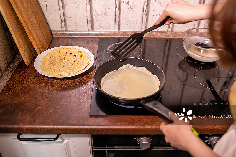 年轻的当代家庭主妇在煎锅上做美味的煎饼作为早餐图片素材