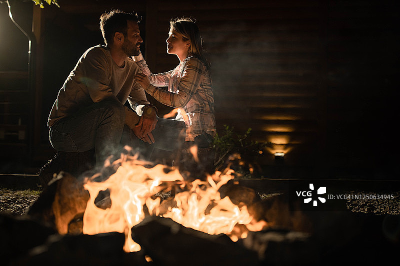 一对浪漫的情侣晚上在后院的篝火旁聊天。图片素材