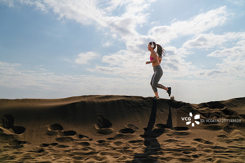 女运动员在沙滩上跑步在炎热的晴天图片素材