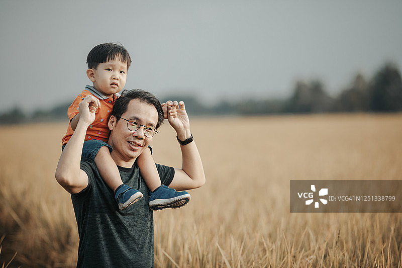 周末早上，一个亚裔华人家庭在稻田里打发闲暇时间，父亲抱着他的孩子，男婴肩上享受图片素材