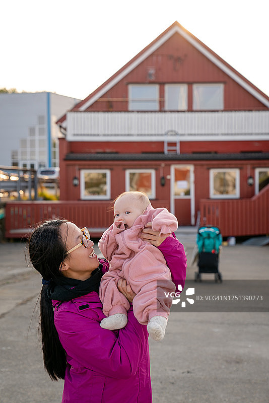 妈妈和婴儿在挪威Henningsvær的码头旁玩耍。图片素材