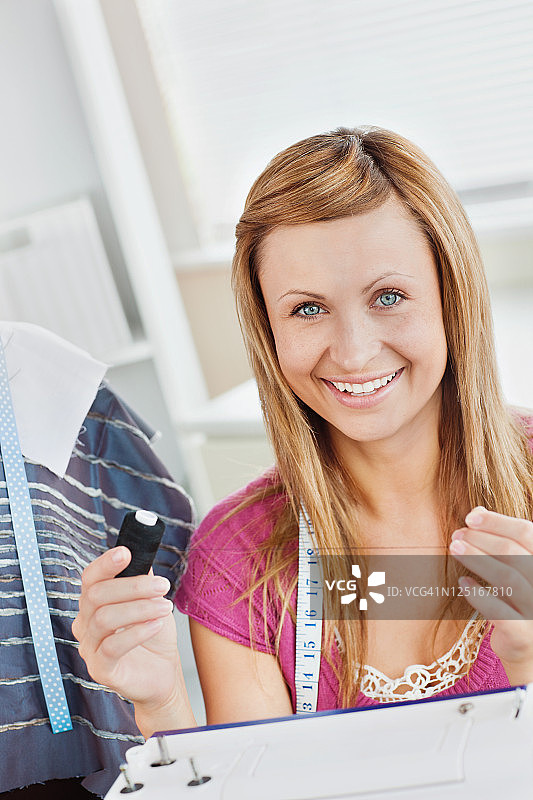 微笑的女人在厨房缝图片素材