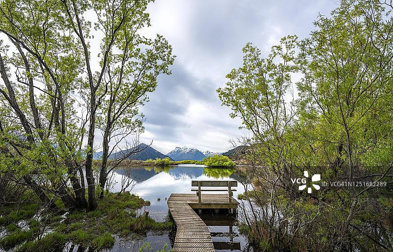 新西兰南岛，皇后镇附近的格伦诺奇泻湖，湖边有码头和木凳，山上倒映在湖中图片素材