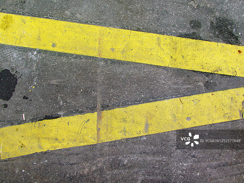 两条黄色的线在巴黎的街道上被涂抹和风化图片素材