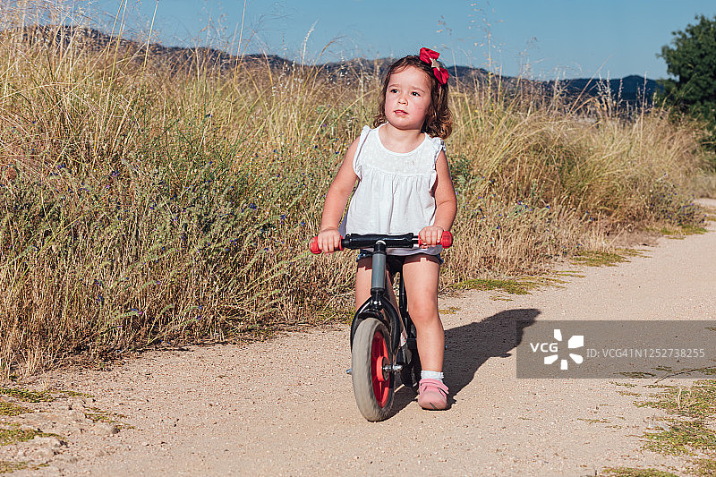 小女孩在一条土路上骑自行车图片素材