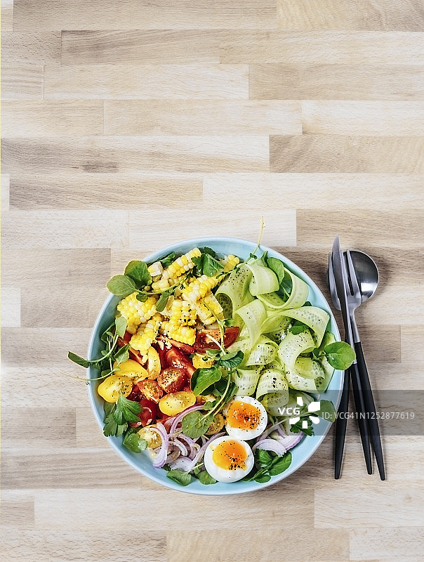 一碗新鲜的沙拉和煮鸡蛋在木制的背景图片素材
