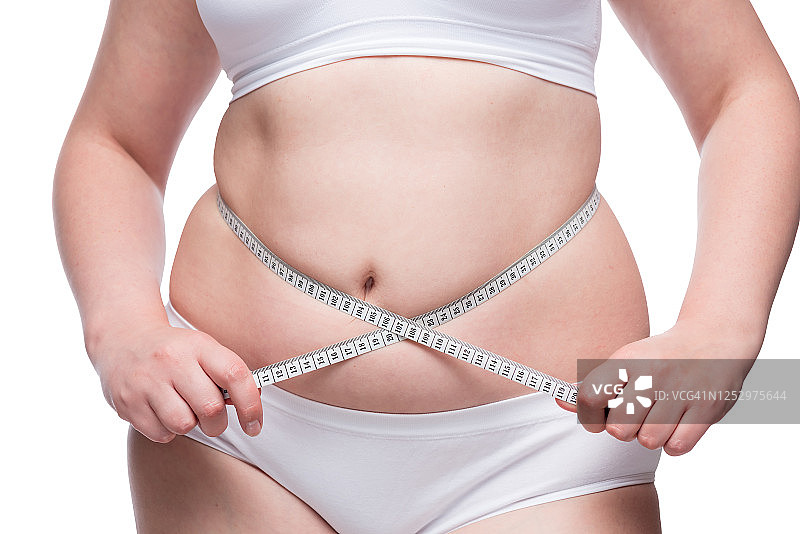 对抗肥胖的概念——用卷尺把腹部的脂肪卷起来图片素材