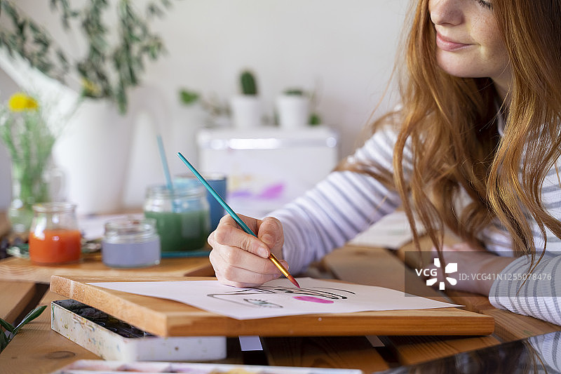 裁剪图像的年轻女子在纸上画在家里图片素材